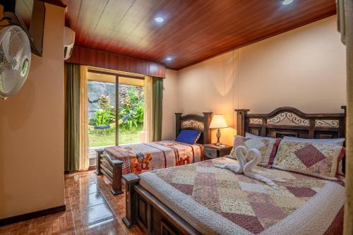a bedroom with two beds and a fan and a window at Aunty Arenal Lodge in Fortuna