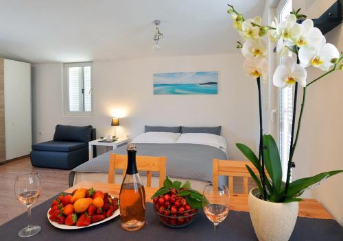 a living room with a table with fruit and a bottle of wine at Sunset Garden House Vrsar in Vrsar