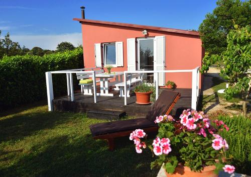 a house with a deck with a bench and flowers at Sunset Garden House Vrsar in Vrsar
