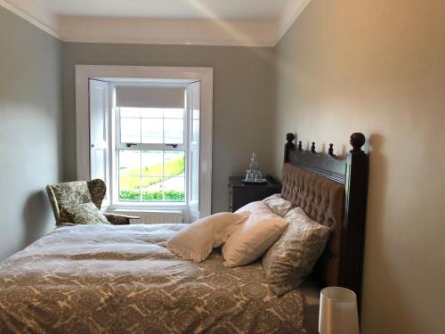 a bedroom with a bed with a chair and a window at Old Parochial House in Dundalk