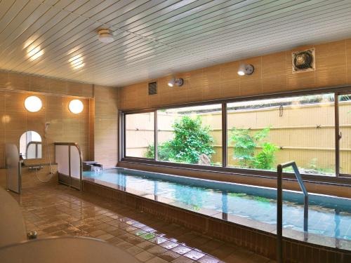 a swimming pool in a building with a large window at Wisterian Life Club Atami in Atami