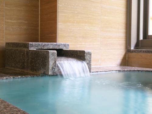 a pool with a water fountain in a building at Wisterian Life Club Atami in Atami