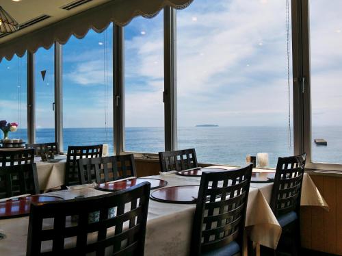 a restaurant with tables and chairs and a view of the ocean at Wisterian Life Club Atami in Atami
