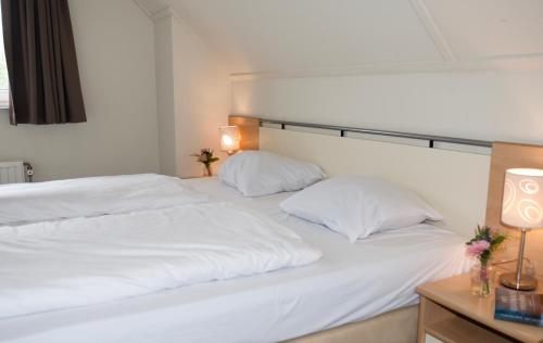 two beds with white sheets and pillows in a room at Antibes 246 - Kustpark Village Scaldia in Hoofdplaat