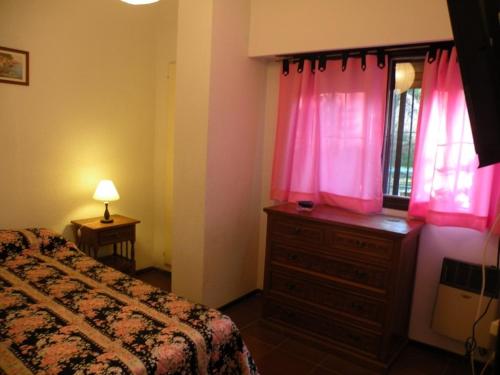 1 dormitorio con 1 cama y vestidor con cortinas rosas en Departamento En Pinamar en Pinamar