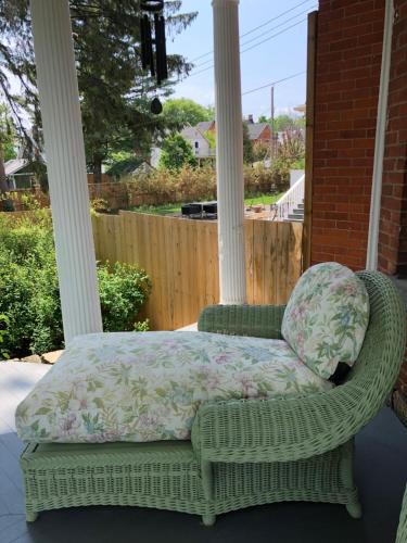 a wicker chair with a pillow on a porch at 1000 Islands Bed and Breakfast-The Bulloch House in Gananoque