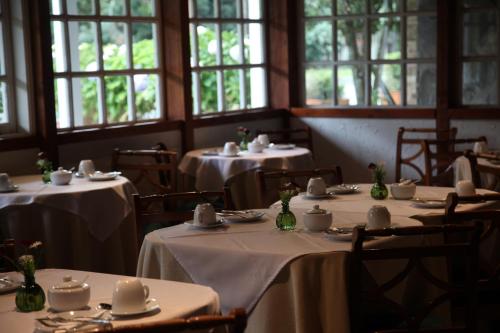 un comedor con mesas y manteles blancos. en Hotel Geronimo, en Pucón