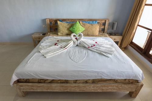 a bedroom with a large bed with white sheets at Koming Guest House in Canggu