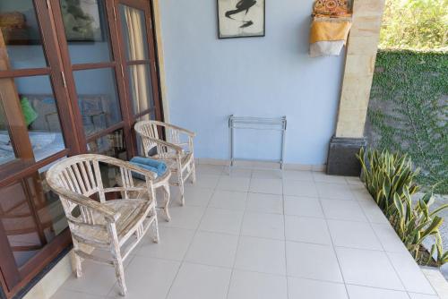 two chairs and a table on a porch at Koming Guest House in Canggu