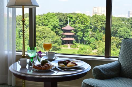 a table with food and a drink and a window at Hotel Chinzanso Tokyo in Tokyo
