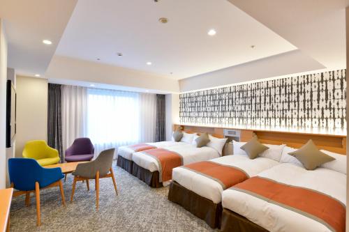 a hotel room with four beds and a desk and chairs at Narita Tobu Hotel Airport in Narita