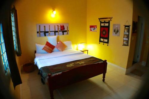 um quarto com uma cama num quarto amarelo em Seven Candles Guesthouse em Siem Reap