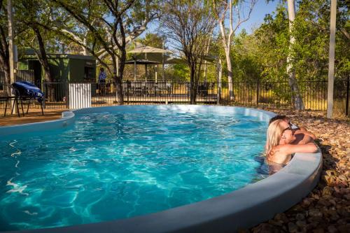 two people laying in a swimming pool at Bungle Bungle Savannah Lodge in Turkey Creek