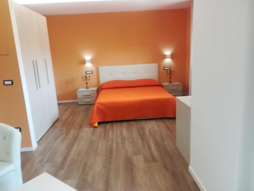 a bedroom with an orange bed and wooden floors at Villa Ulivi in Filiano