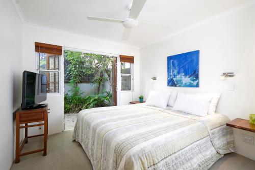 a white bedroom with a bed and a tv at Allambi Apartment 2, 25 Allambi Rise, Little Cove in Noosa Heads