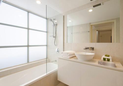 een badkamer met een wastafel, een bad en een spiegel bij Allambi Apartment 2, 25 Allambi Rise, Little Cove in Noosa Heads