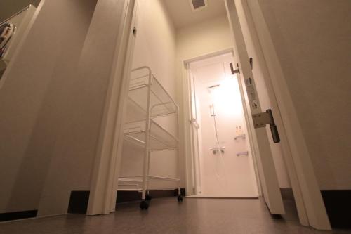 a hallway with a white door and a shelf at Mezame Hostel in Nagasaki