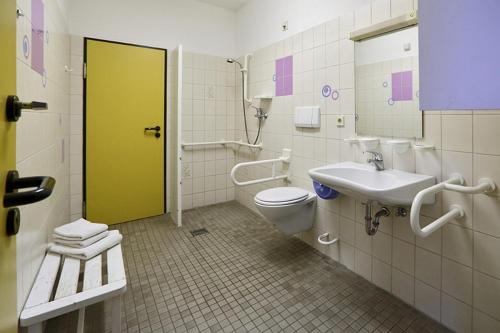 a bathroom with a toilet and a sink and a yellow door at Hostel Flensburg in Flensburg