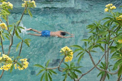 a man is swimming in a swimming pool at Grand Zuri Kuta Bali in Kuta