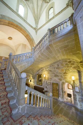 a spiral staircase in a building with a stone wall at Parador de Plasencia in Plasencia
