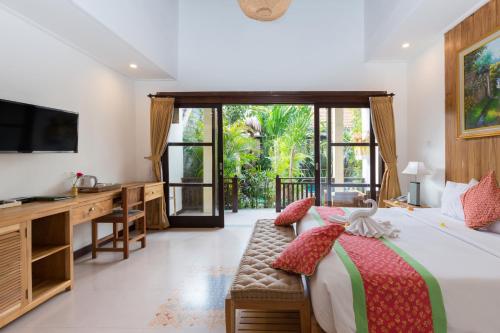 a bedroom with a bed and a desk and a television at Meruhdani Boutique Hotel Ubud in Ubud