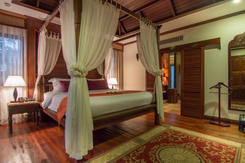 a bedroom with a canopy bed with curtains at Angkor Palace Suite & Villa in Siem Reap
