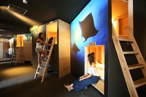 two girls are climbing up bunk beds in a room at Guest House Chura Cucule Ishigakijima in Ishigaki Island