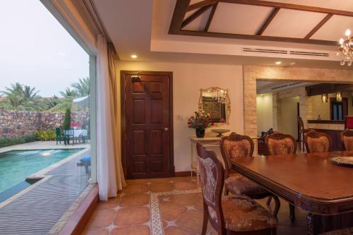 a dining room with a table and a swimming pool at Angkor Palace Suite & Villa in Siem Reap