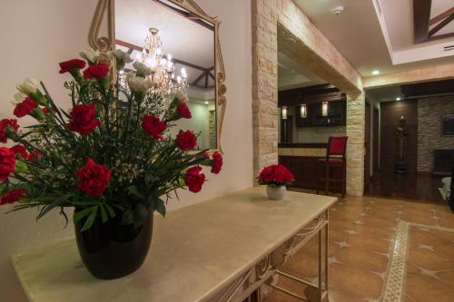 a vase with red flowers on a table in a room at Angkor Palace Suite & Villa in Siem Reap