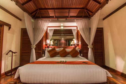 a bedroom with a large white bed with curtains at Angkor Palace Suite & Villa in Siem Reap