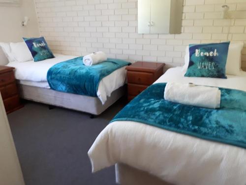 a bedroom with two beds with blue and white sheets at Villa Seven in Kalbarri