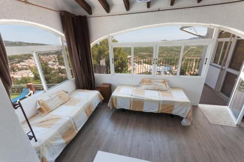 a bedroom with two beds and a large window at Llumicel in Ador