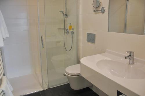 a bathroom with a shower and a toilet and a sink at Garni Hotel Alber in Marktl