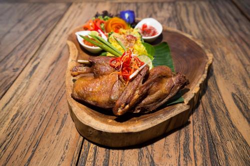 a plate of food with a chicken and salad on a table at Meruhdani Boutique Hotel Ubud in Ubud