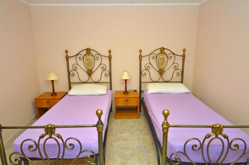 2 camas en un dormitorio con sábanas moradas y 2 lámparas en Casa Baia Verde, en Patù