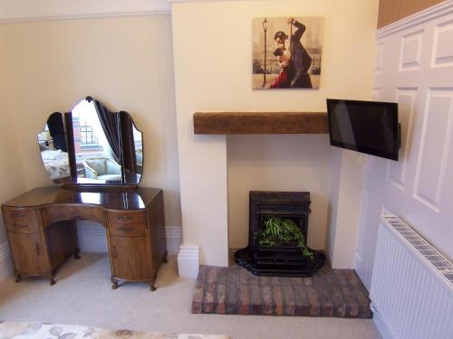 a room with a desk and a mirror and a television at The Hollies in Bridlington