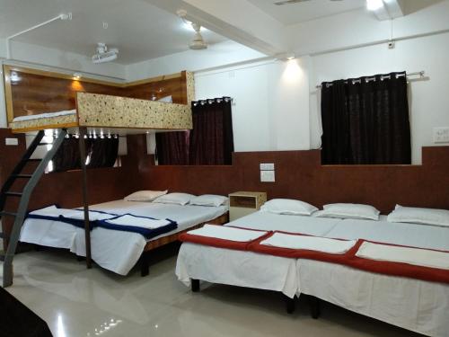 a room with three beds and a ladder in it at Joshi Yatri Niwas in Kolhapur