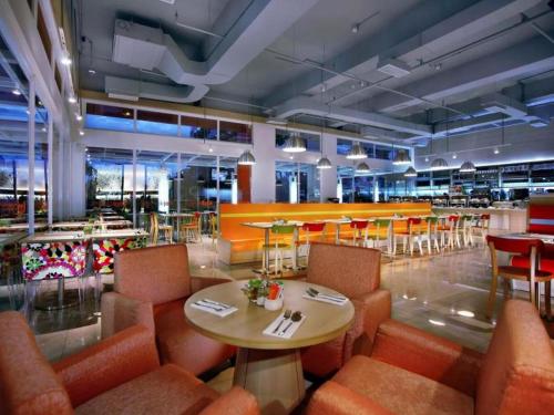 un restaurante con sillas naranjas, mesa, mesas y sillas en Zuri Express Lippo Cikarang, en Cikarang