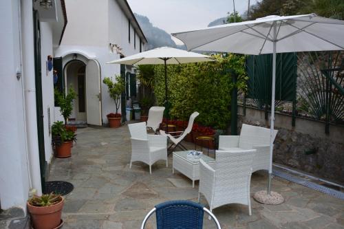a patio with white chairs and an umbrella at Le Cicale - Apartments in Conca dei Marini