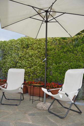 two white chairs and an umbrella on a patio at Le Cicale - Apartments in Conca dei Marini