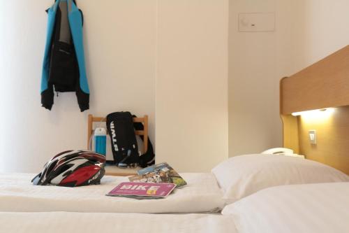 a bed with a backpack and a book on it at Hotel Villa Clara in Nago-Torbole