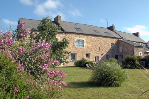 a large brick house with pink flowers in the yard at Clos St Ange (Dinan-St Malo) in Vildé-Guingalan