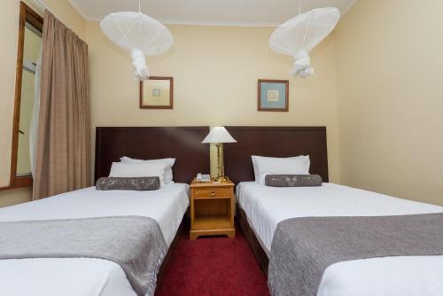 a hotel room with two beds and a red carpet at Sunbird Mzuzu in Katoto