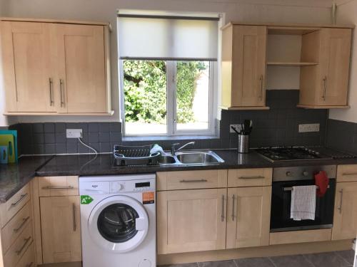 a kitchen with a washing machine and a sink at Raven House by RentMyHouse in Hereford
