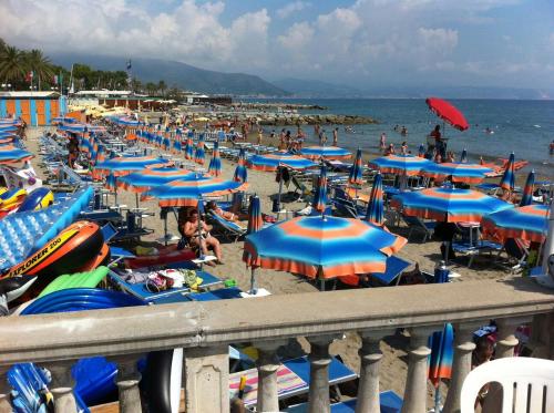 a beach with many blue umbrellas and people on it at Hotel Pescetto in Albenga