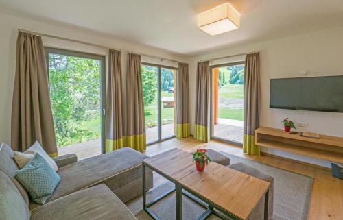 a living room with a couch and a tv at Das Leonhard - Naturparkhotel am Weissensee in Weissensee