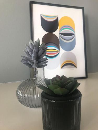 a vase and a plant on a table with a picture at Timehouse Serviced Apartments in Munich