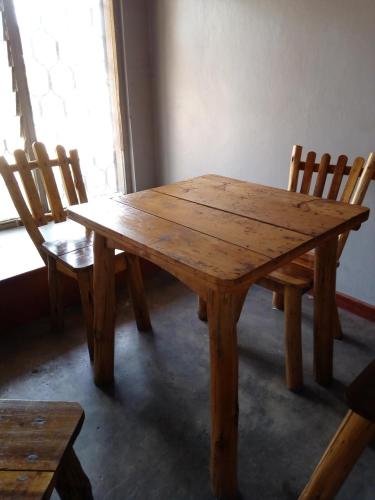 a wooden table and chairs in a room at Mbunga Community Tourism Campsite in Kasese