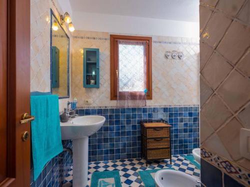 bagno piastrellato blu con lavandino e specchio di La Casa sul Mare a Olbia