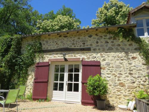 a stone cottage with a red and white door at Le Moulin de Pensol - Gites in Pensol